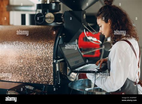 Coffee Roaster Machine And Barista Woman With Laptop At Coffee Roasting