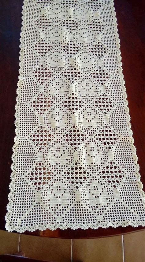 A White Crocheted Table Runner Sitting On Top Of A Wooden Floor