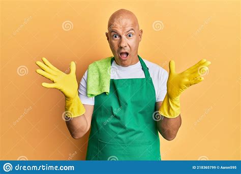 Middle Age Bald Man Wearing Apron Holding Cleaning Gloves Celebrating