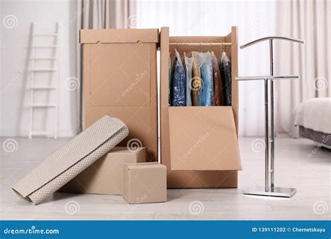 Cardboard Wardrobe Boxes With Clothes On Hangers And Carpet Indoors