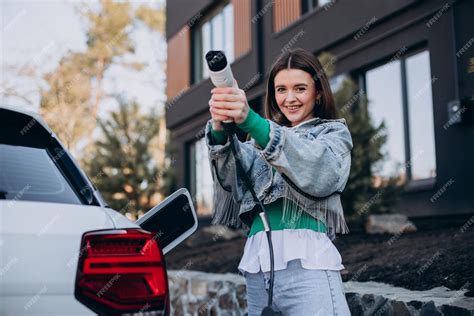 充電ピストルで電気自動車を充電している女性 無料の写真