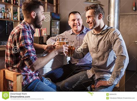 Amigos Felices Que Beben La Cerveza En El Contador En Pub Foto De