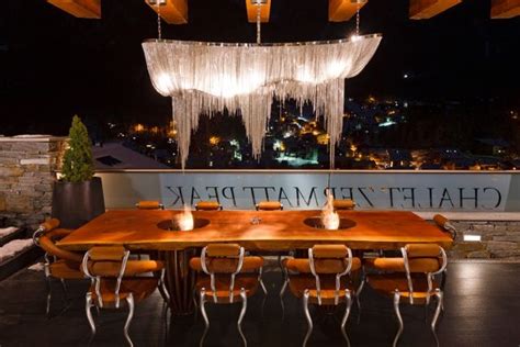 A Wooden Table Surrounded By Chairs And Lights In Front Of A Sign That