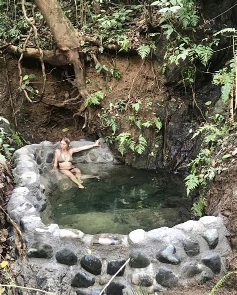 A Woman Sitting In The Middle Of A Small Pool Surrounded By Trees And