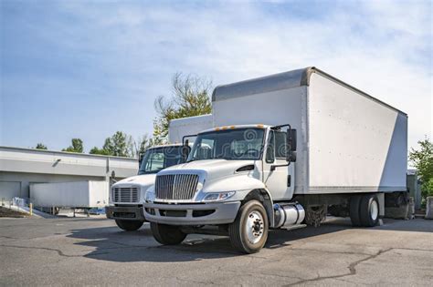 Middle Duty Day Cab White Rigs Semi Trucks With Box Trailers Standing In Row With Dry Van Semi