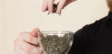 A Man Holding A Glass Bowl Filled With Dried Herbs And Looking At The