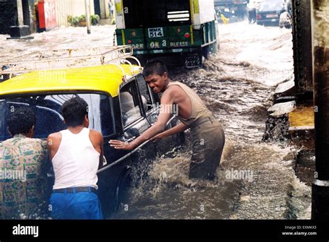 People Push A Taxi Stranded In The Flooded Waters Due To Heavy Rains At