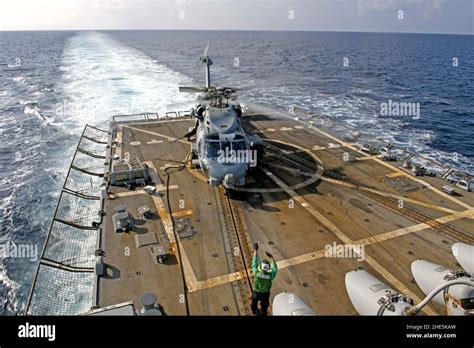 Sailor Signals To The Pilot Of A MH 60R Sea Hawk Helicopter After