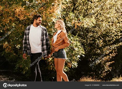 Young Happy Couple Holding Hands Looking Each Other While Walking Stock