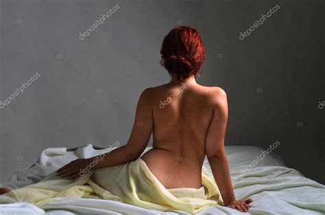 Vista Trasera De Una Mujer Desnuda Sentada En La Cama Cubierta De