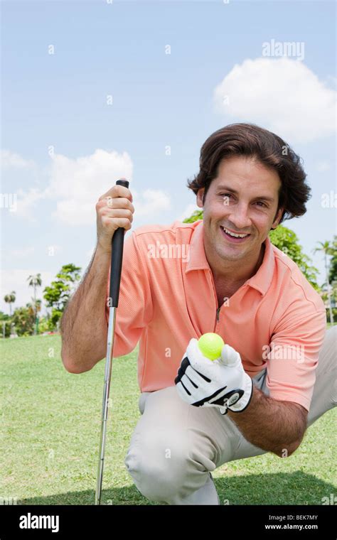 Portrait Of A Mid Adult Man Holding A Golf Ball And A Golf Club Stock