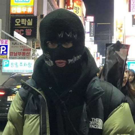 A Person Wearing A Black Mask And Jacket In The Street At Night Time