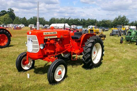 An Old Red Farmall Tractor Parked In A Field With Other Antique