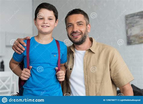 Retrato Del Padre Y Del Hijo Sonrientes Con La Mochila En Casa De Nuevo