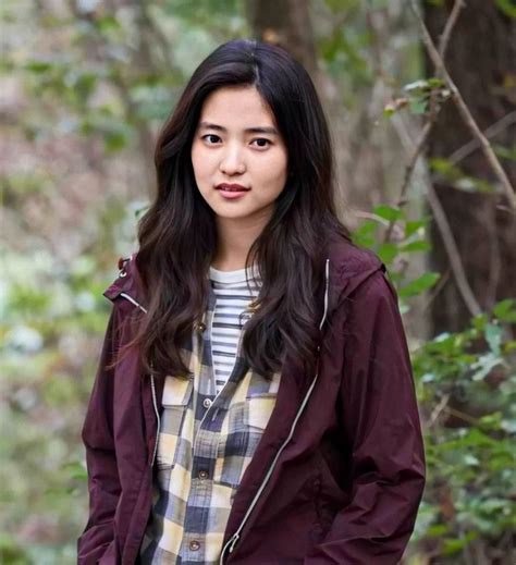 A Woman Standing In The Woods Wearing A Jacket