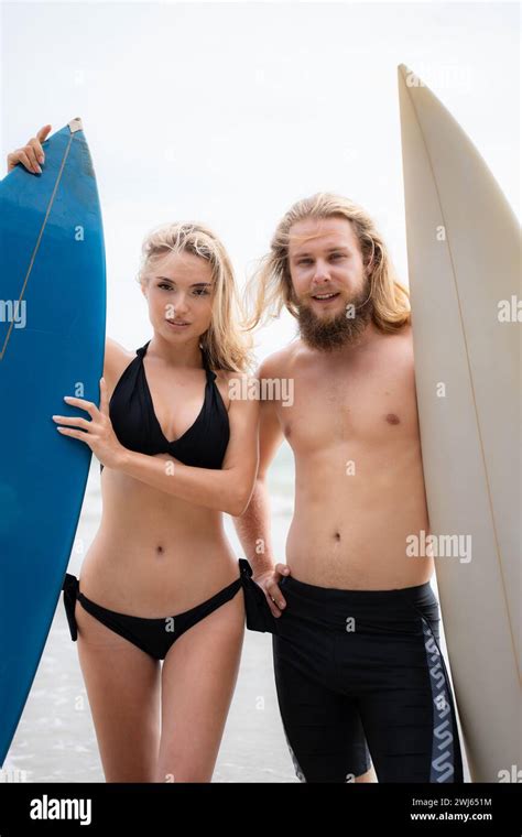 Couple Of Surfers Holding Surfboards On The Beach Man And Woman In