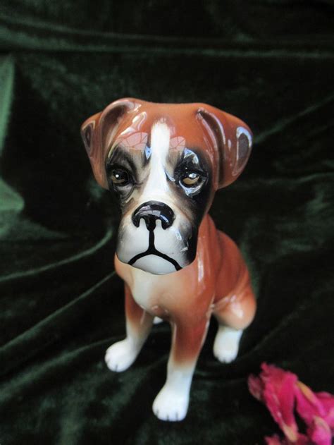 A Figurine Of A Dog Sitting On Top Of A Green Cloth Next To Pink Flowers