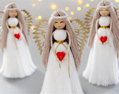 Three Angel Figurines With Hearts In Their Hands On A White Surface