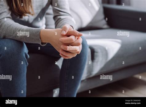 Unrecognizable Female Folded Hands On Knees Together Sitting On Couch Alone Upset Depressed