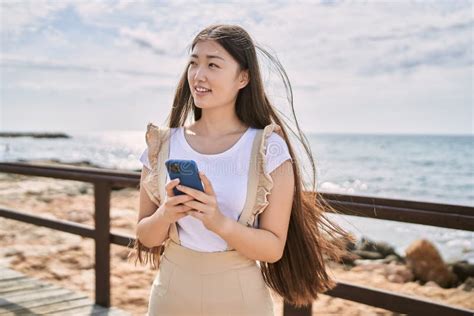 Jovencita China Sonriendo Feliz Usando Un Smartphone En La Playa Foto