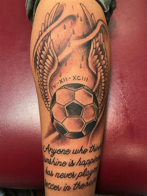 A Tattoo On The Leg Of A Person With A Soccer Ball And Wings Around It