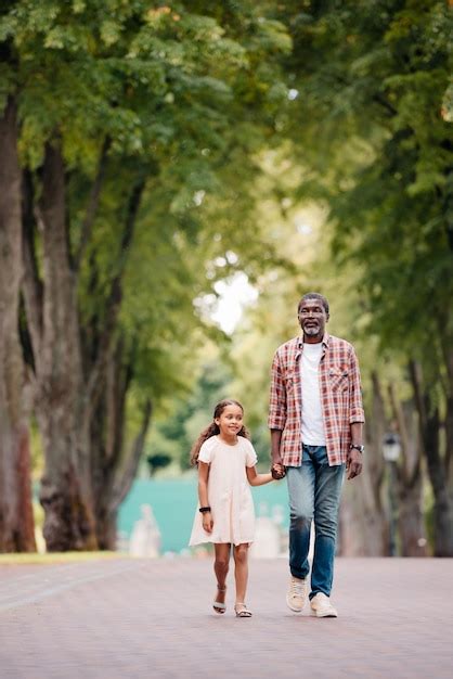 Ni A Afroamericana Cogida De La Mano Con El Abuelo Y Caminando En El