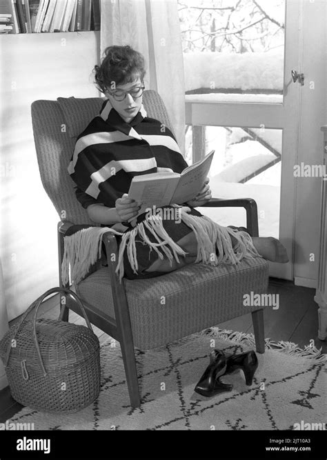 Dans Le 1950s Une Jeune Femme à La Maison Est Assise Dans Un Fauteuil