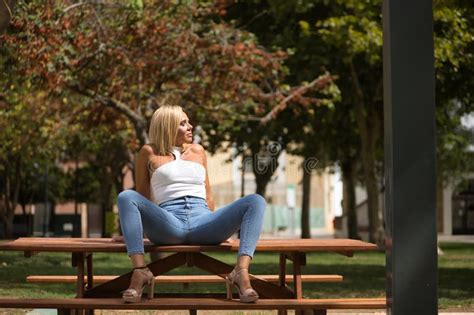 Mature Woman Beautiful Blonde With White Top And Jeans With Closed Eyes Sunbathing Sitting