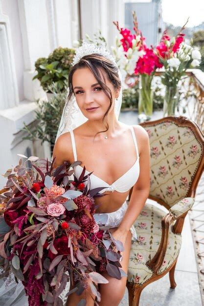 Uma bela jovem em lingerie requintada fica na varanda de um prédio de vários andares e tem um