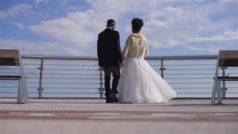 African American Happy Newlyweds Walking In Slow Motion To Bridge