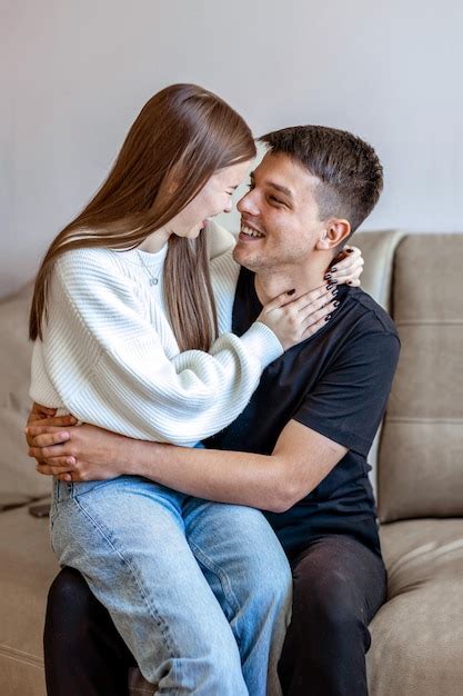 Son felices feliz pareja joven sentada en el sofá abrazándose y riendo