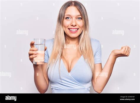 Jeune belle fille blonde boire un verre d eau criant fier célébrant la victoire et le succès