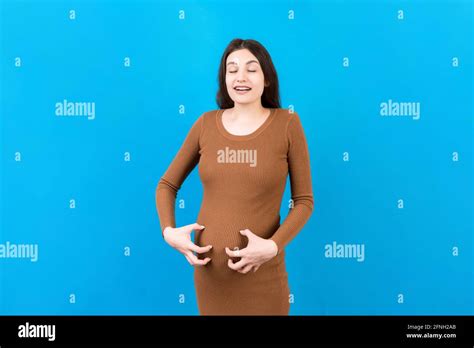 Pregnant Woman Scratching Her Belly On Colored Background Stock Photo