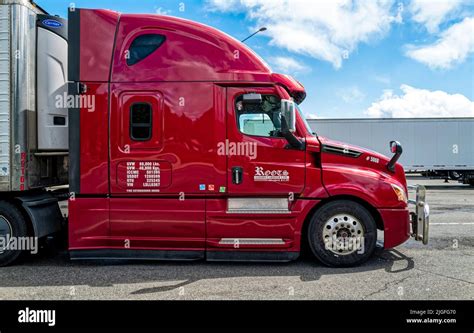 The Passenger Side Of A Red Freightliner Cascadia Semi Truck Parked In