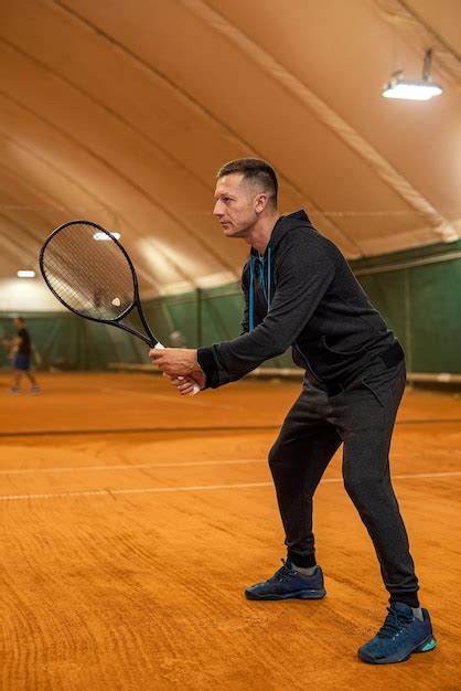 Retrato de cuerpo entero de un ágil atleta masculino jugando al tenis