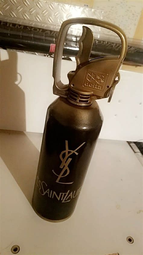 A Black And Gold Water Bottle Sitting On Top Of A Counter Next To A Knife