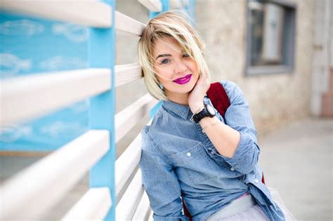 Portrait de femme blonde souriante rêveuse avec des cheveux courts et des lèvres rose vif