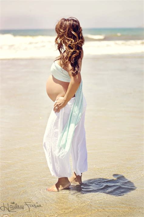 A Pregnant Woman Is Standing In The Water At The Beach With Her Belly Wrapped Up