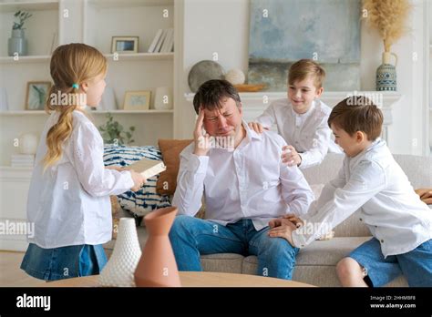 Tired Father Sitting On Couch In Living Room Feels Annoyed And