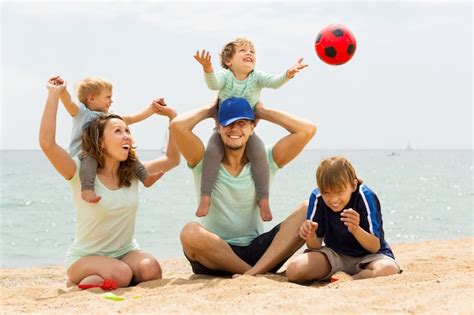 Familia Positiva De Cinco Jugando En La Playa Del Mar Foto Gratis