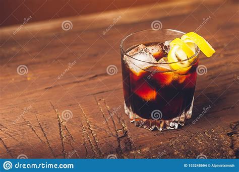 Strong Alcoholic Drink Of Brandy Whiskey In A Glass With Ice Cubes On A Dark Wooden Background