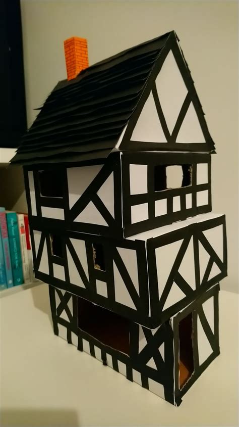 a black and white model of a house on top of a table next to books