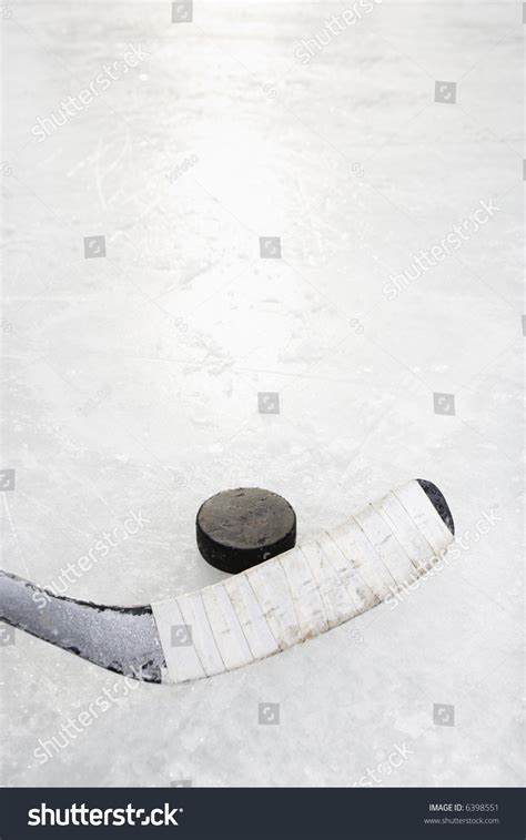 Close Up Of Ice Hockey Stick On Ice Rink In Position To Hit Hockey Puck