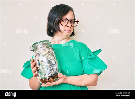 Brunette Woman With Down Syndrome Holding Jar With Savings Clueless And