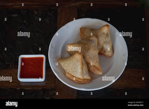 Samosas on a white plate with dipping spicy red sauce Stock Photo - Alamy