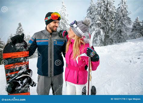 Couple Skiing And Snowboarding Enjoying In Snowy Mountains Together