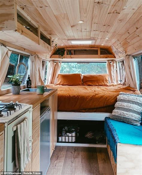 The Interior Of A Small Camper With Wood Paneling And Bed In The Foreground