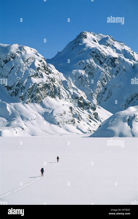 Skiers Cross Frozen Surface Of Lake Harris Along The Routeburn Track In