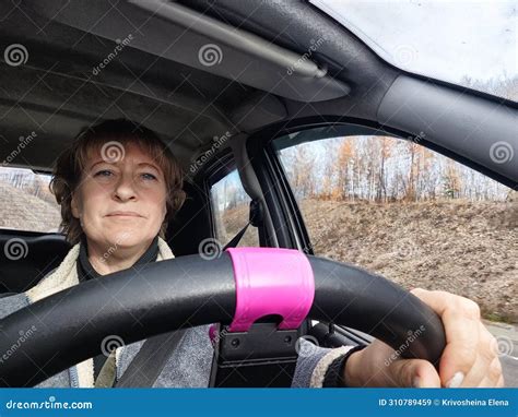 A Funny Cute Blonde Girl Or A Middle Aged Woman Driving A Car In Summer