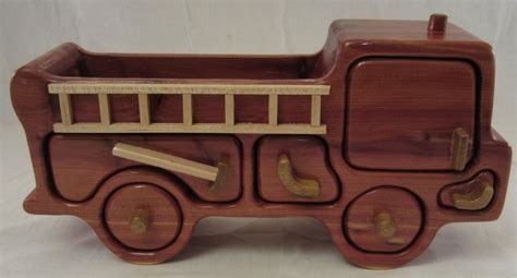 A Wooden Toy Firetruck Is Shown On A White Background With Wood Trimmings